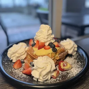 a plate of french toast topped with strawberries, blueberries, and powdered sugar