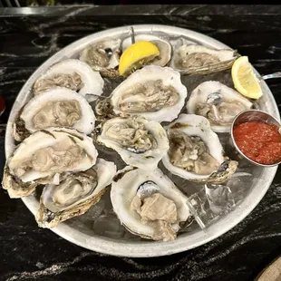a plate of oysters with a side of sauce