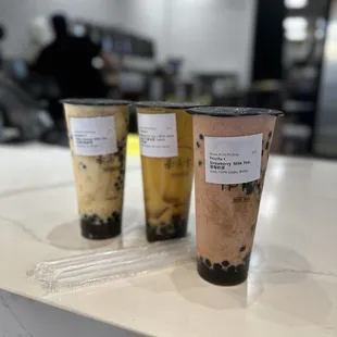 three cups of iced coffee on a counter