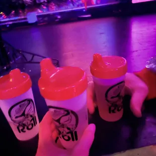 a hand holding three cups of coffee