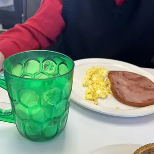 Ham steak and scrambled eggs, green cup filled with variety of creamers!