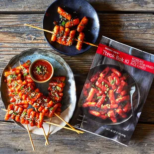 a plate of chicken skewers and a cookbook