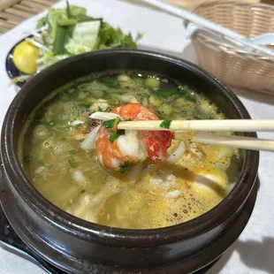 a bowl of soup with chopsticks