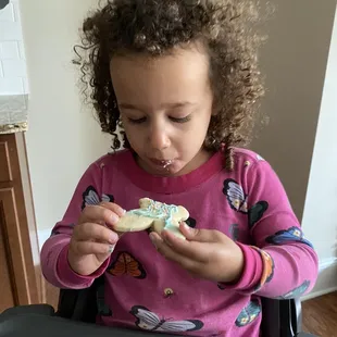 a little girl eating a cookie