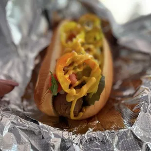 a hot dog covered in cheese and peppers