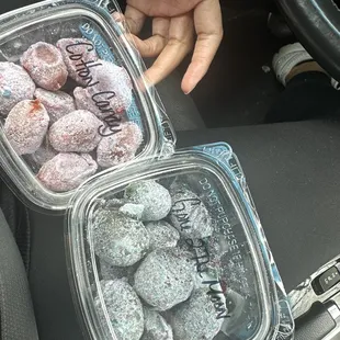 a person holding a plastic container filled with doughnuts