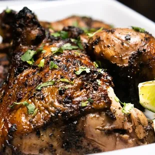 a plate of chicken with lime wedges