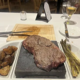 Rib eye steak cooking on a hot lava rock table side.