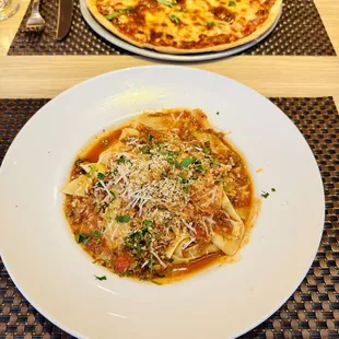 two plates of pasta and a pizza