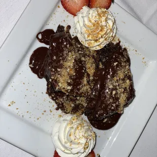 a chocolate dessert with whipped cream and strawberries