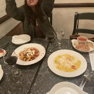 a woman sitting at a table with plates of food