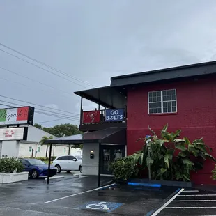 a red building with a black roof and a blue car parked in front of it