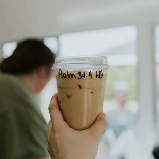 a hand holding a cup of iced coffee
