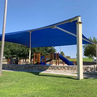 Playground equipment under large sunshade.