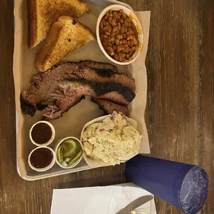 Brisket plate with beans, potato salad, Texas toast, and pickels.