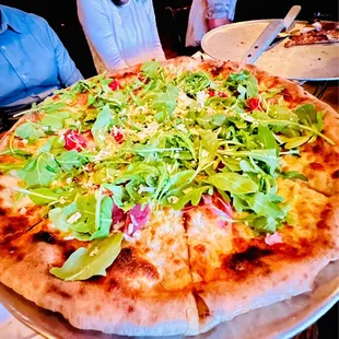 a pizza with greens on it