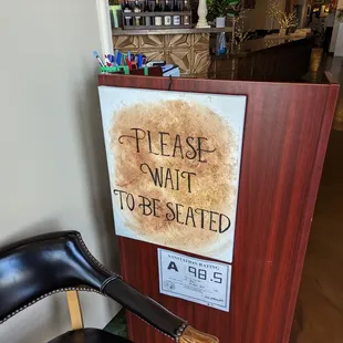 a sign that reads please wait to be seated