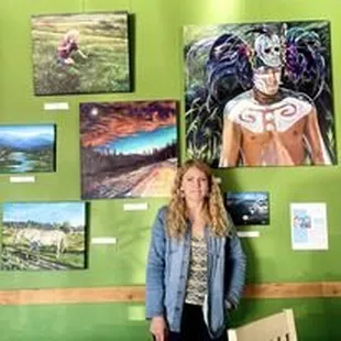 a woman standing in front of a wall of paintings