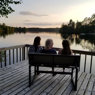 three people sitting on a bench overlooking a lake