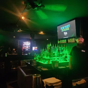 a man behind a bar with green lights