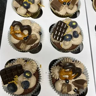 a variety of cupcakes decorated with chocolate and pretzels