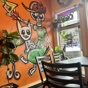 a restaurant with a mural of skeletons on the wall