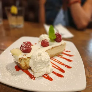a piece of cake with whipped cream and raspberries