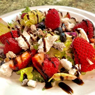 a salad with strawberries, blueberries, and goat cheese