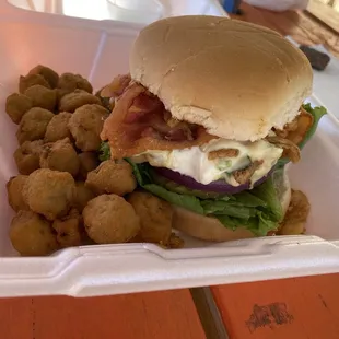 a sandwich and tater tots in a styrofoam container