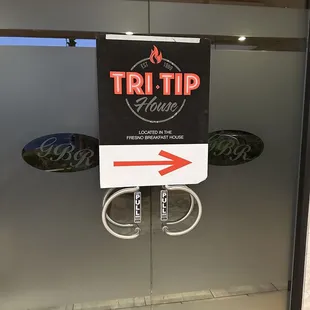 a tri - tip sign in a glass door