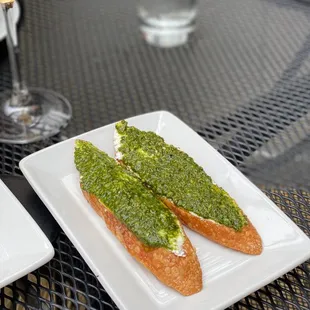 a plate of bread with pesto and a glass of wine