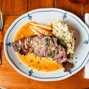 a plate of food with meat, rice and carrots