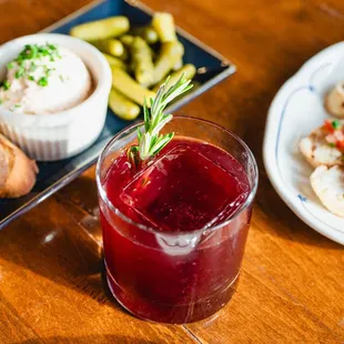 a glass of red wine with a sprig of rosemary