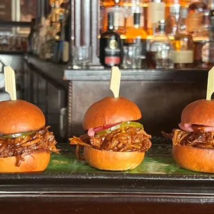 three pulled pork sandwiches on a tray