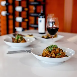 two bowls of food and a glass of wine