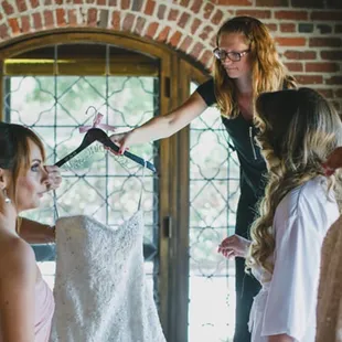 Tricia bringing my gown down from the hanging hook, just after a gown photo was taken and right before I&apos;m about to put it on!