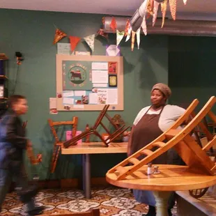 a woman standing in front of a table with chairs