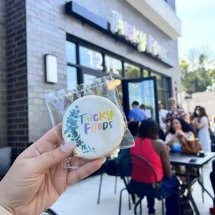 a person holding a cookie in front of a restaurant