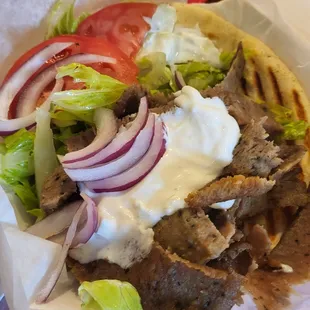 a taco with meat, onions, lettuce, tomato, and sour cream
