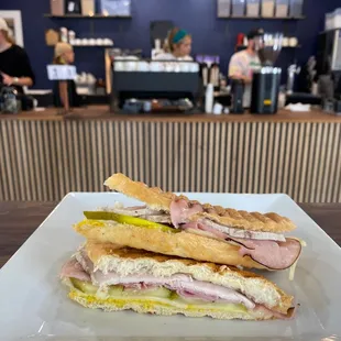 Cuban sandwich with ham, roasted pork, Swiss cheese, yellow mustard and dill pickles.