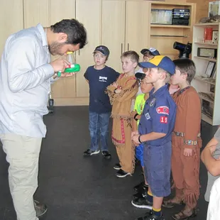 Michael shows the kids how to look through the magnifying tool to see the small pond critters that they captured.