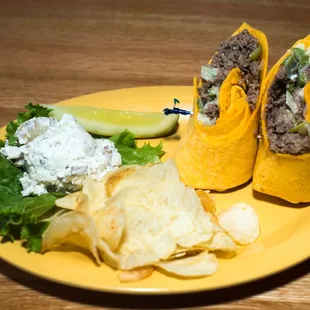 a plate of food including tortillas, chips and a pickle
