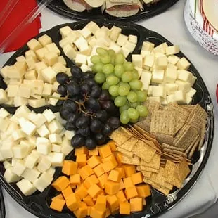 a platter of cheese, crackers and grapes