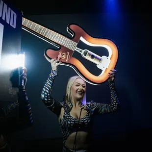 a woman holding up a guitar