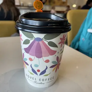 a coffee cup with a lid and a flower design