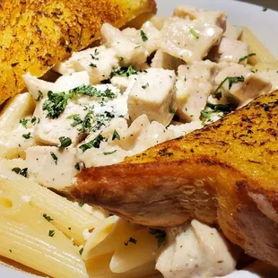 a plate of pasta with chicken and bread