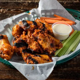 a basket of chicken wings with carrots and celery