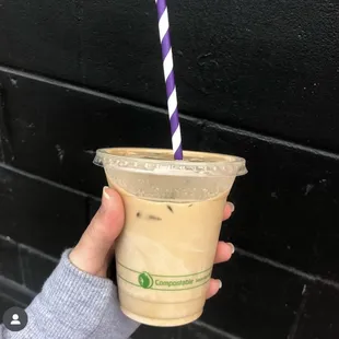 a hand holding a cup of iced coffee