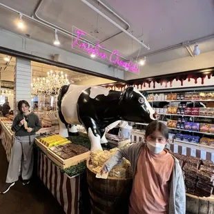 a woman and a child standing in front of a cow statue