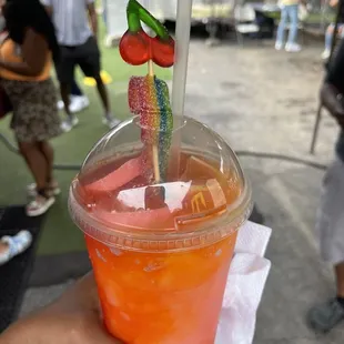 a person holding a drink with gummy straws